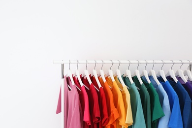 Photo of Rack with bright clothes on white background. Rainbow colors