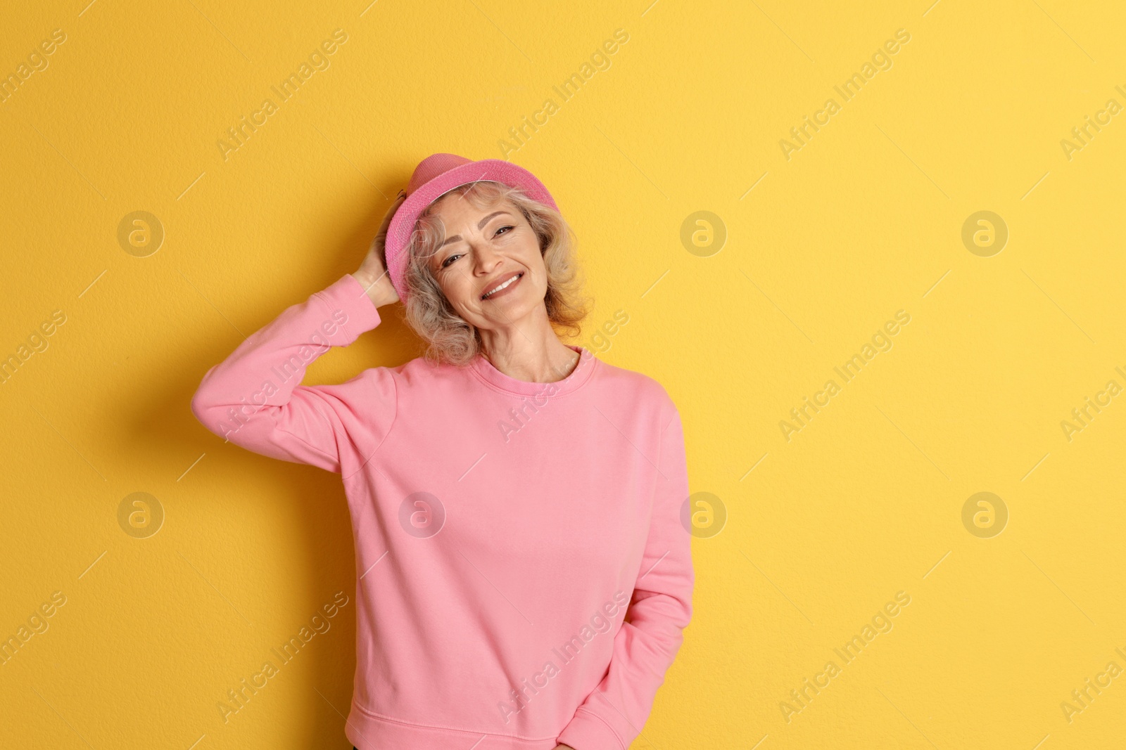 Photo of Portrait of mature woman in hipster outfit on color background. Space for text