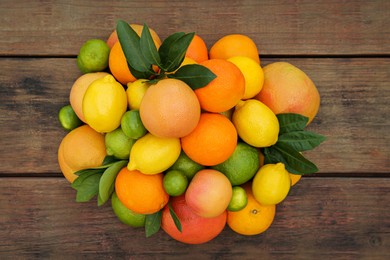 Different citrus fruits and leaves on wooden table, flat lay