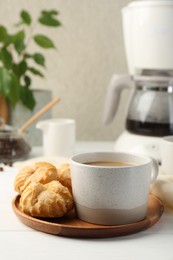 Photo of Aromatic coffee in cup and tasty profiteroles on white wooden table