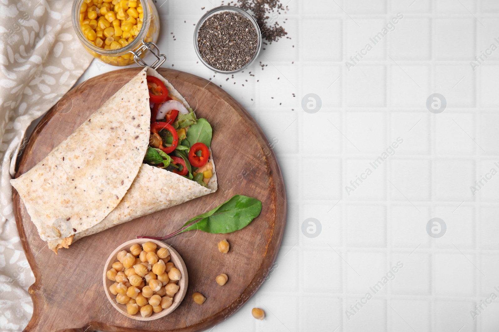 Photo of Board with delicious hummus wrap and vegetables on white table, flat lay. Space for text