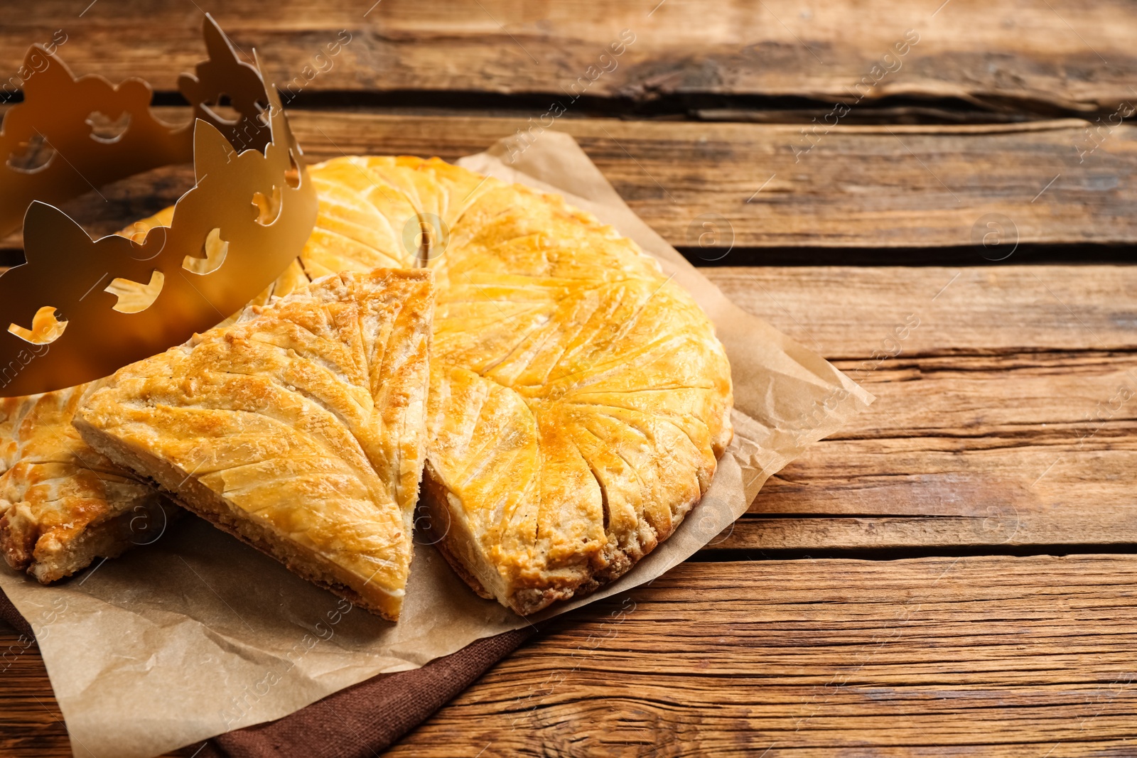 Photo of Traditional galette des Rois with paper crown on wooden table