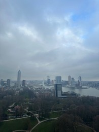Picturesque view of city with modern buildings and park on cloudy day
