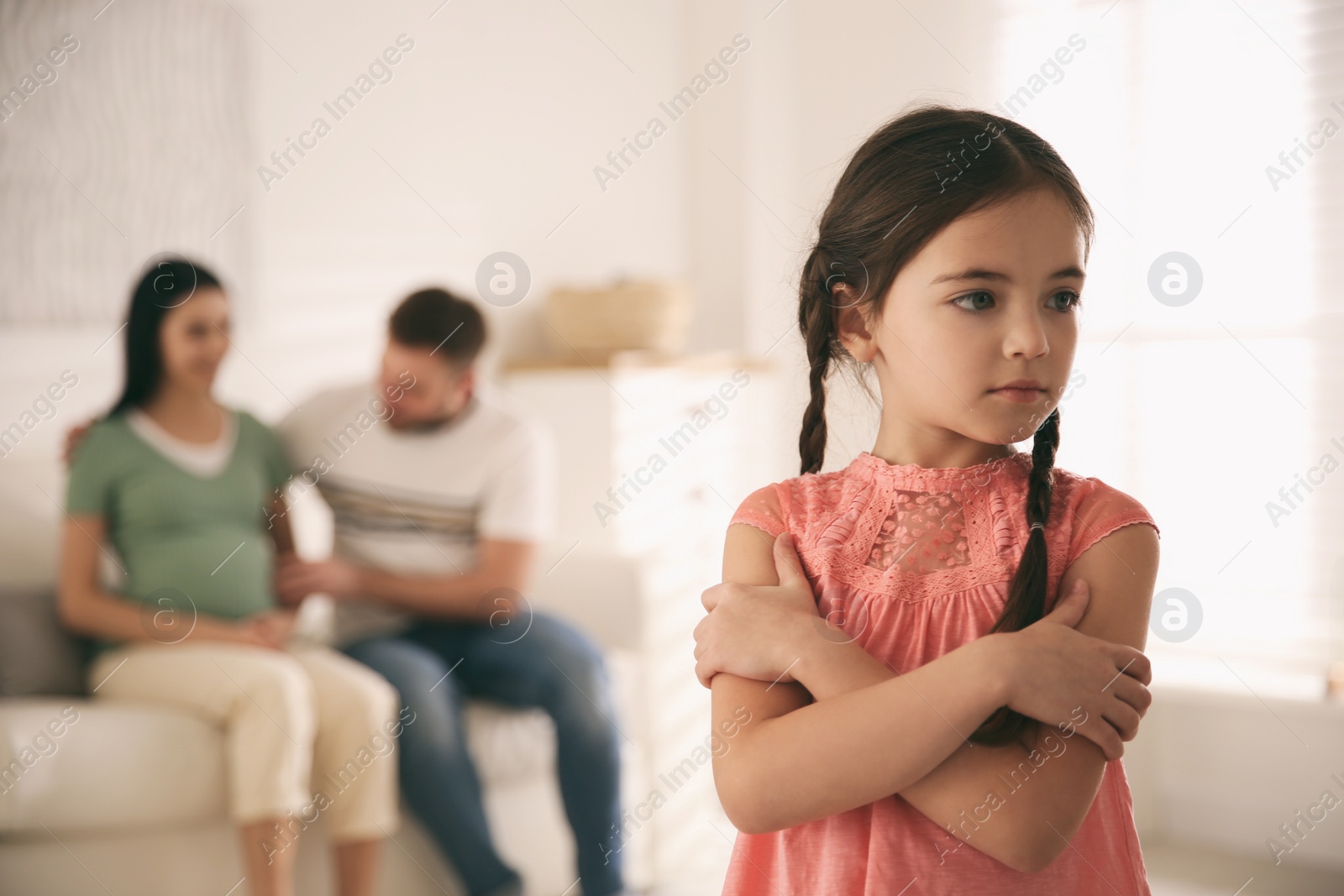 Photo of Unhappy little girl and her father with pregnant mother at home. Feeling jealous towards unborn sibling