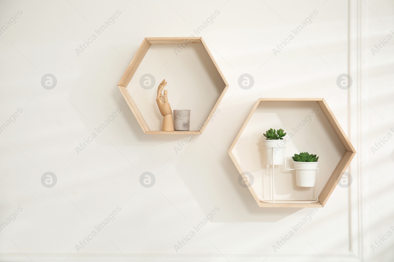 Photo of Honeycomb shaped shelves with decorative elements and houseplants on white wall