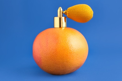 Photo of Grapefruit with vintage atomizer imitating perfume on blue background