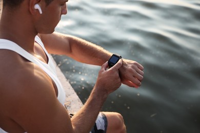 Man checking fitness tracker after training near river, closeup