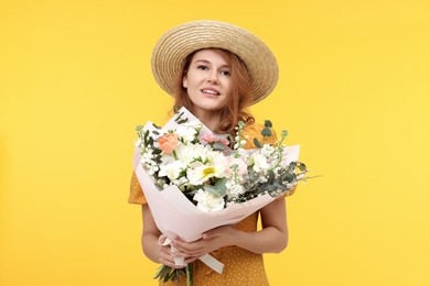 Photo of Happy woman in straw hat with bouquet of beautiful flowers on yellow background