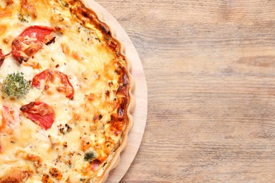 Photo of Tasty quiche with tomatoes and cheese on wooden table, top view. Space for text