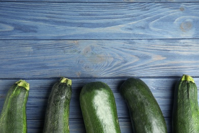 Photo of Fresh ripe green zucchinis on blue wooden table, flat lay. Space for text