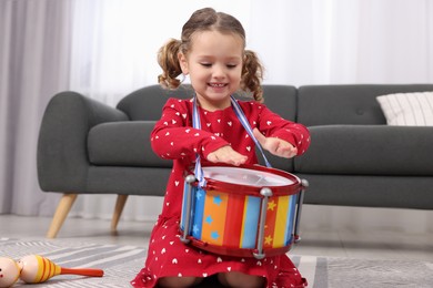 Little girl playing toy drum at home