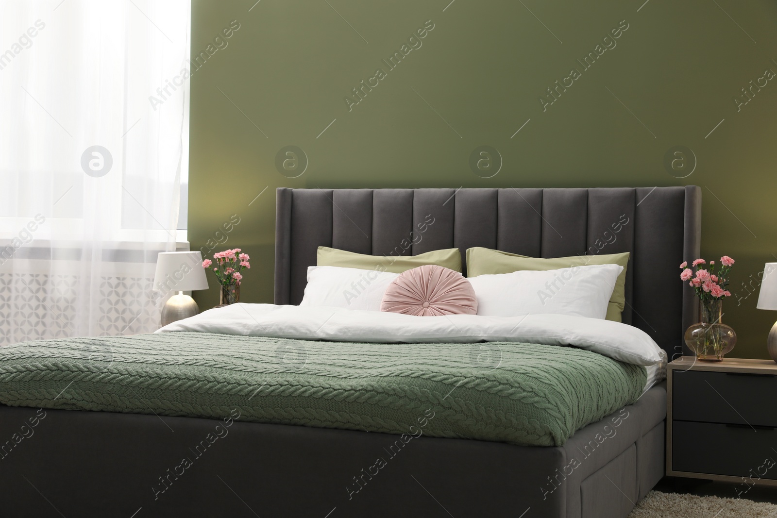 Photo of Large comfortable bed, lamps and beautiful flowers in stylish room. Interior design