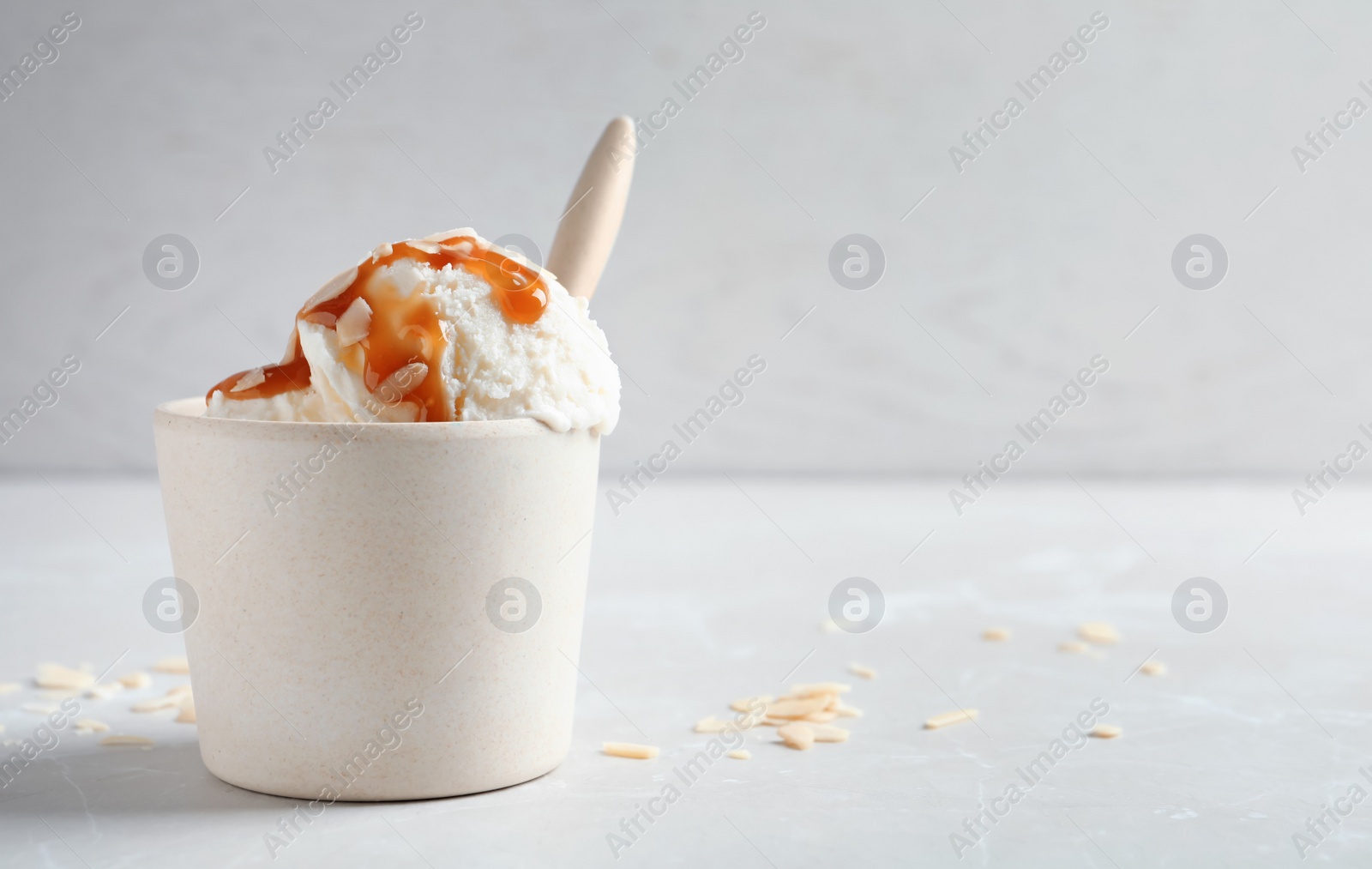 Photo of Bowl with caramel ice cream on light background