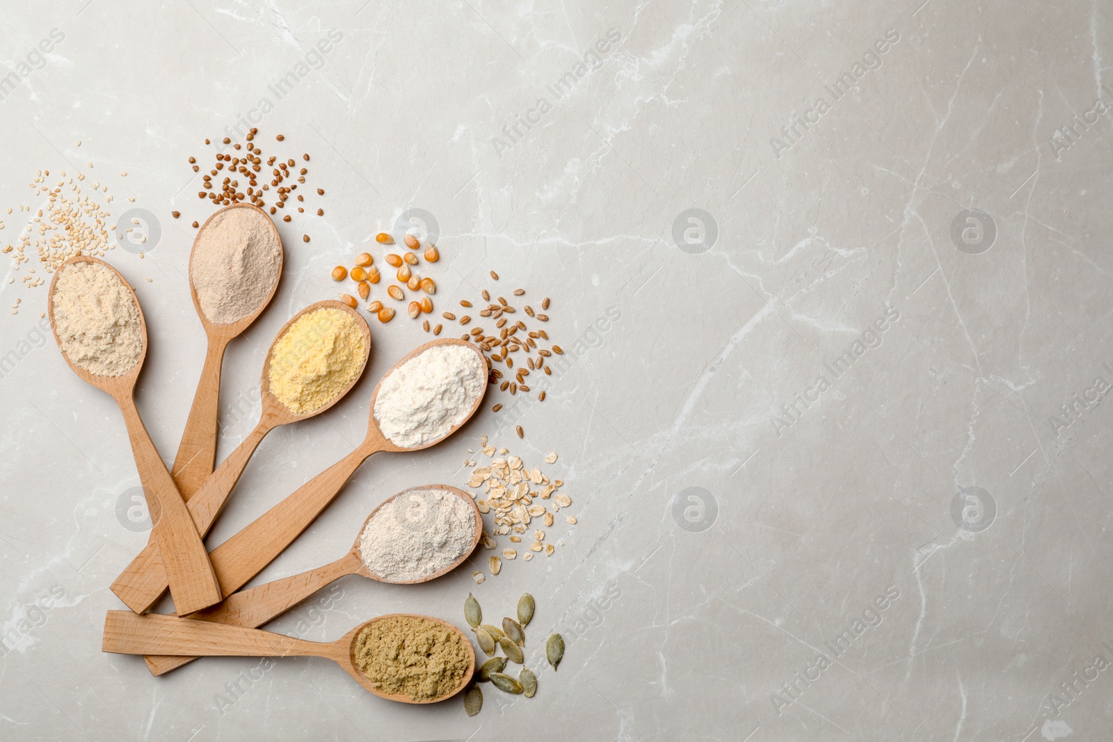 Photo of Spoons with different types of flour on light background