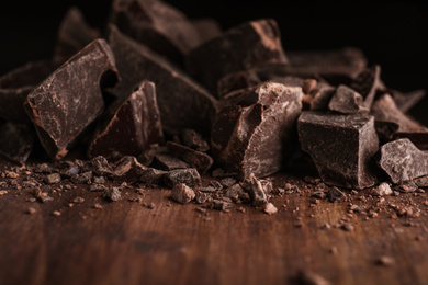 Photo of Pieces of dark chocolate on wooden table, closeup