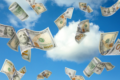 Image of Falling American dollars and blue sky on background. Money rain