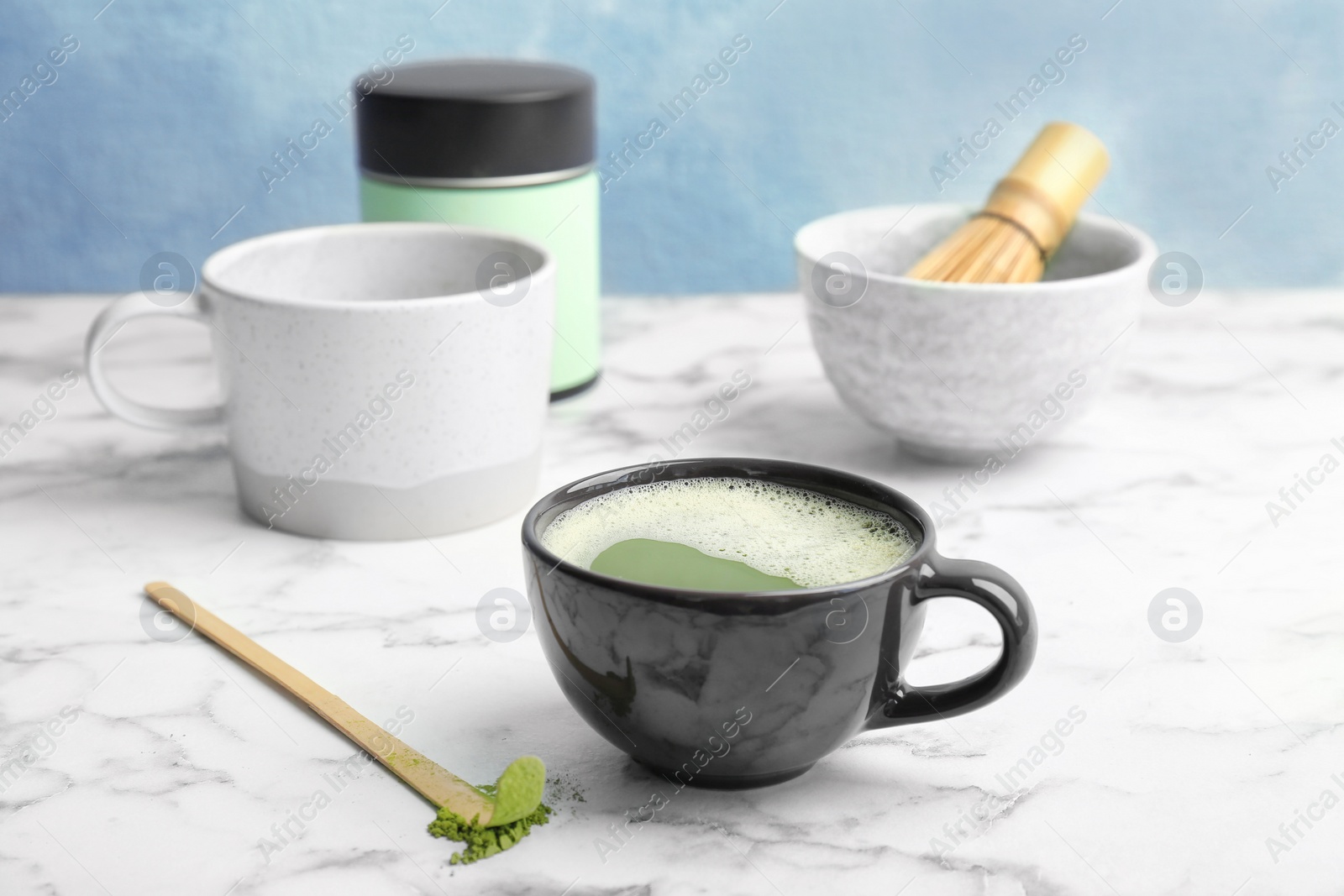 Photo of Cup of fresh beverage and matcha spoon with powdered tea on table