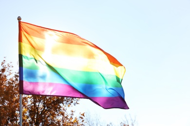 Photo of Rainbow LGBT flag and space for text on blue sky background. Gay rights movement