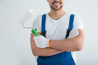 Photo of Man holding paint roller in empty room, closeup
