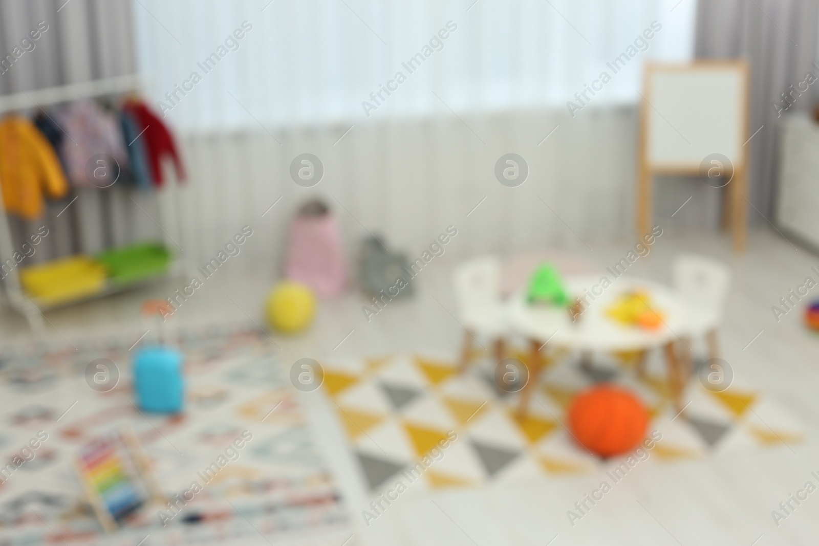 Photo of Blurred view of child`s playroom with different toys and furniture. Stylish kindergarten interior