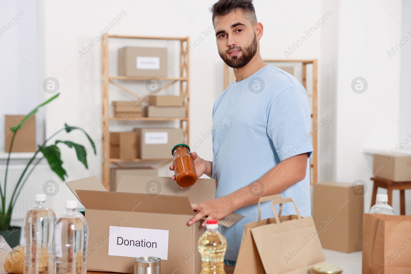 Photo of Volunteer packing food products at table in warehouse