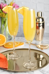 Photo of Glasses of Mimosa cocktail with garnish on white marble table