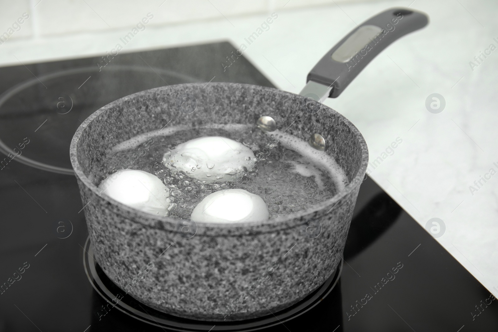 Photo of Boiling chicken eggs in saucepan on electric stove