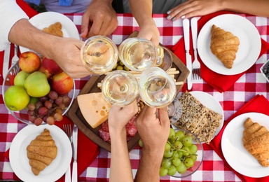 Young people having picnic at table in park, top view