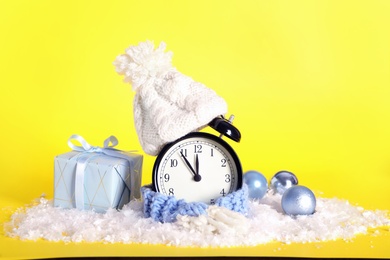 Photo of Vintage alarm clock with Christmas decor on yellow background. New Year countdown