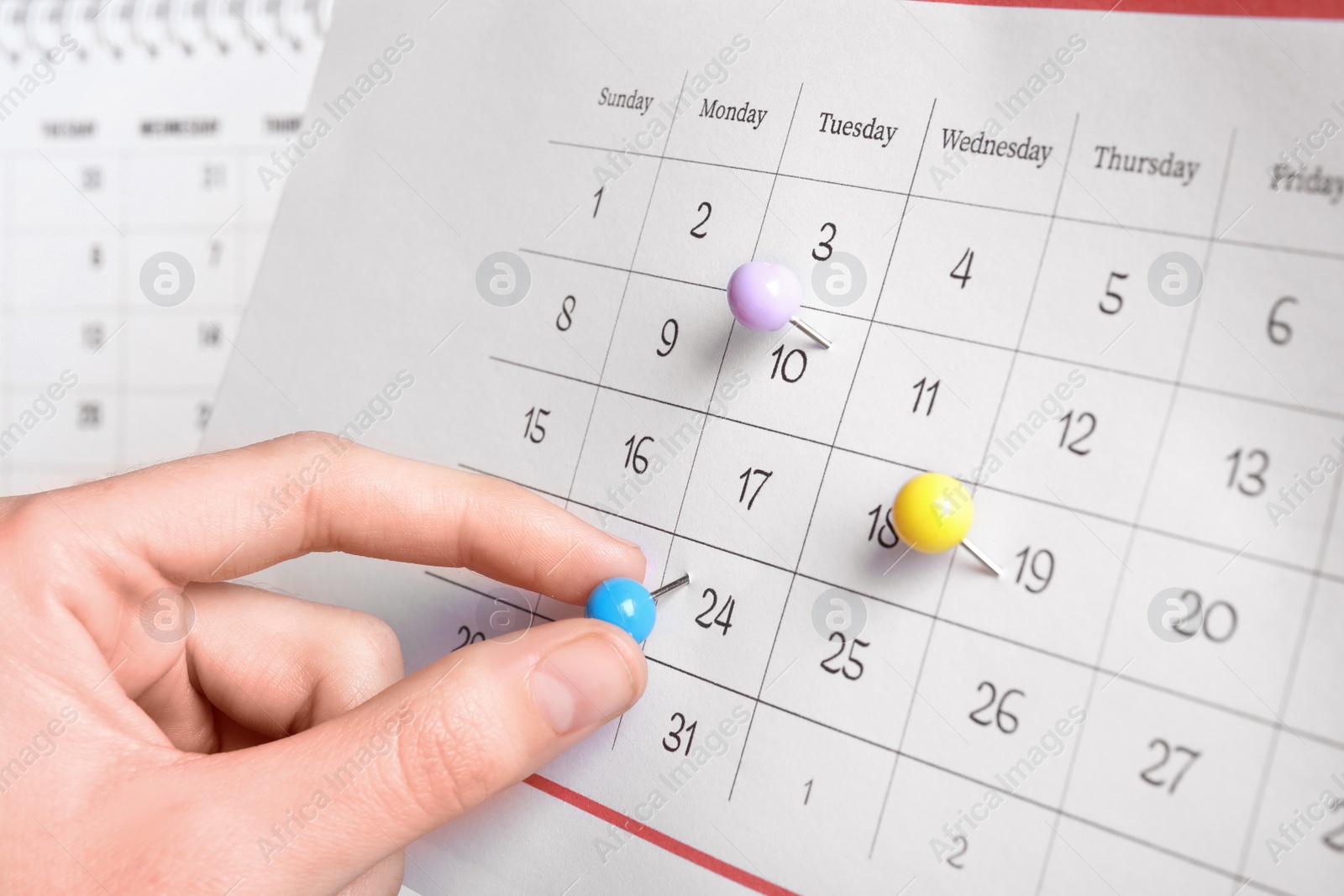 Photo of Woman marking date in calendar with drawing pin, closeup