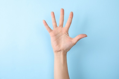 Photo of Woman showing number five on color background, closeup. Sign language