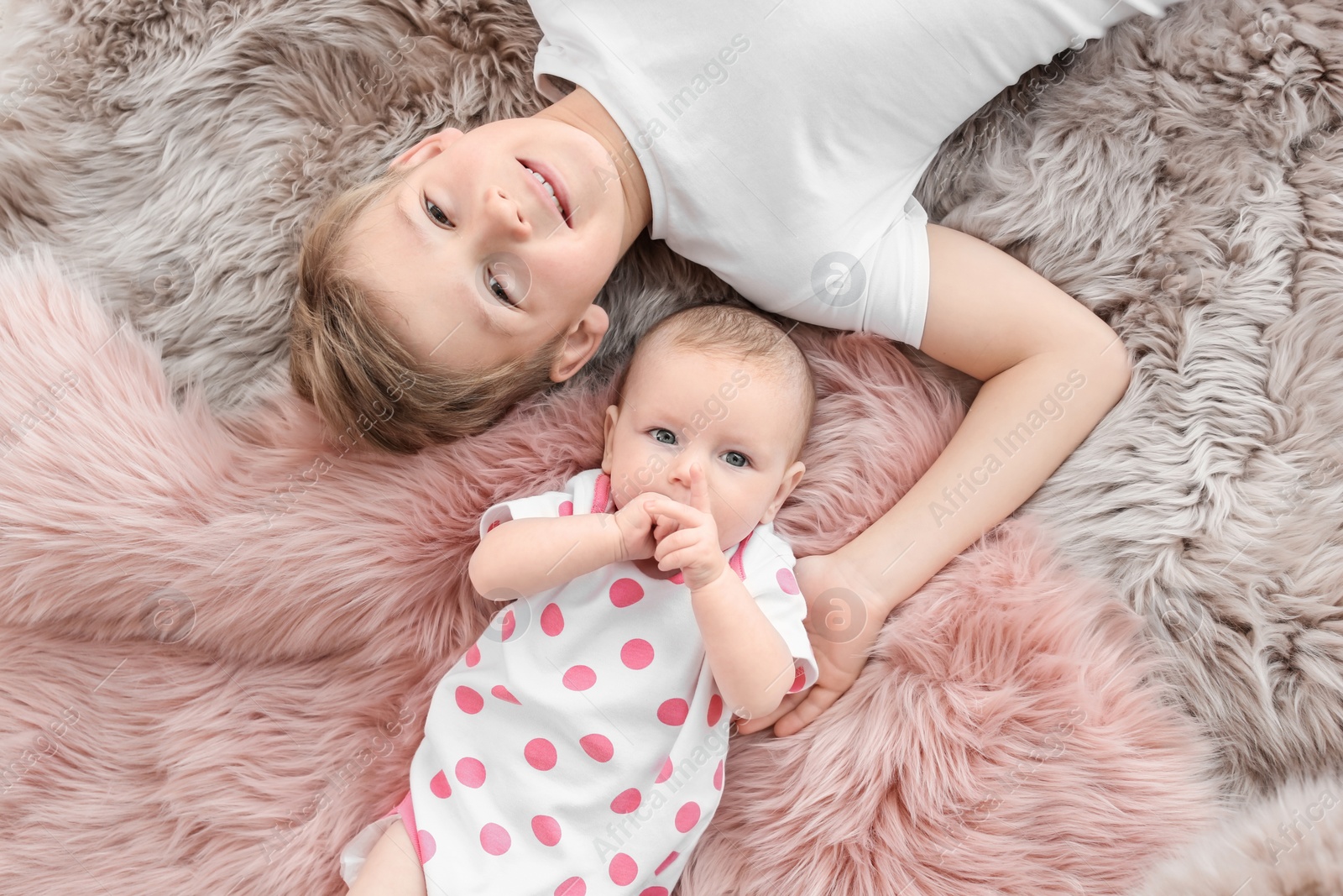 Photo of Cute little baby with elder brother lying on soft fluffy plaid at home