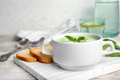 Photo of Green pea soup in bowl on wooden board