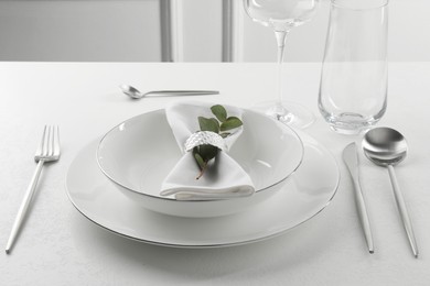 Stylish setting with cutlery and napkin on white textured table