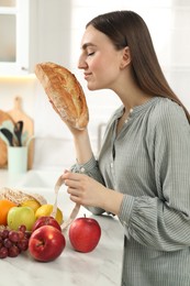 Photo of Woman with bread and string bag of fresh fruits at light marble table