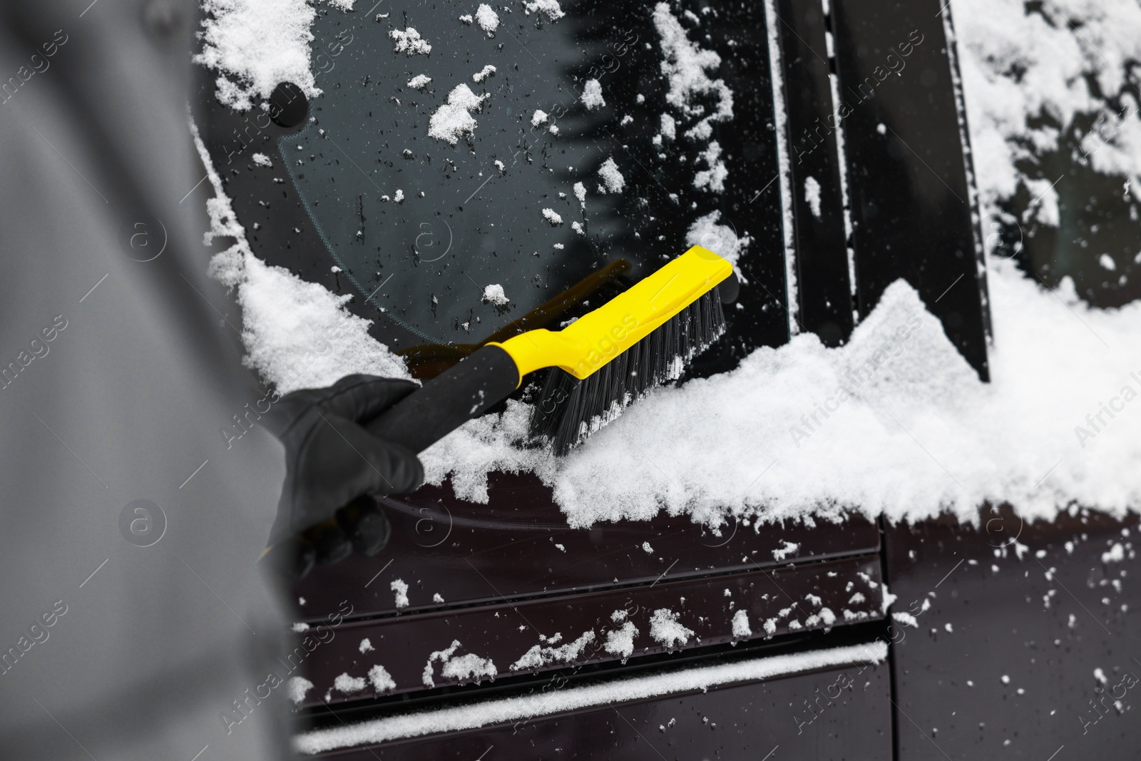 Photo of Man cleaning snow from car window outdoors, closeup