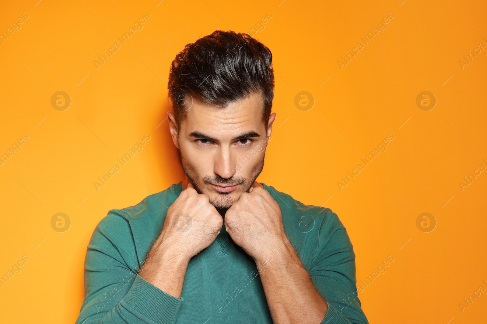 Photo of Young man with trendy hairstyle posing on color background