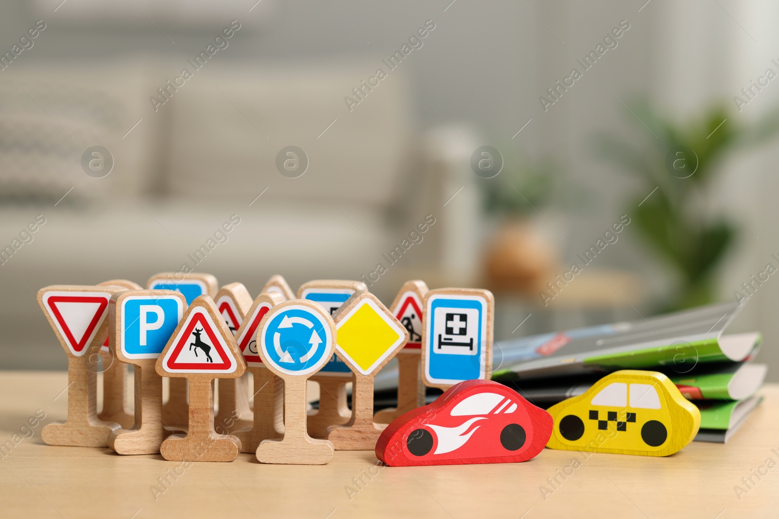 Photo of Set of wooden road signs and cars on table indoors, closeup. Children's toys