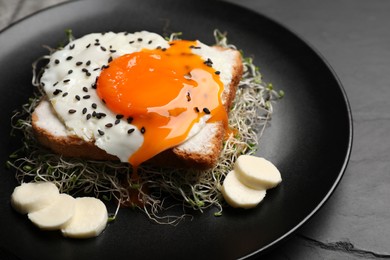 Photo of Tasty toast with egg, cheese and microgreens on light black table