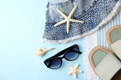 Flat lay composition with beach accessories on light blue background, space for text
