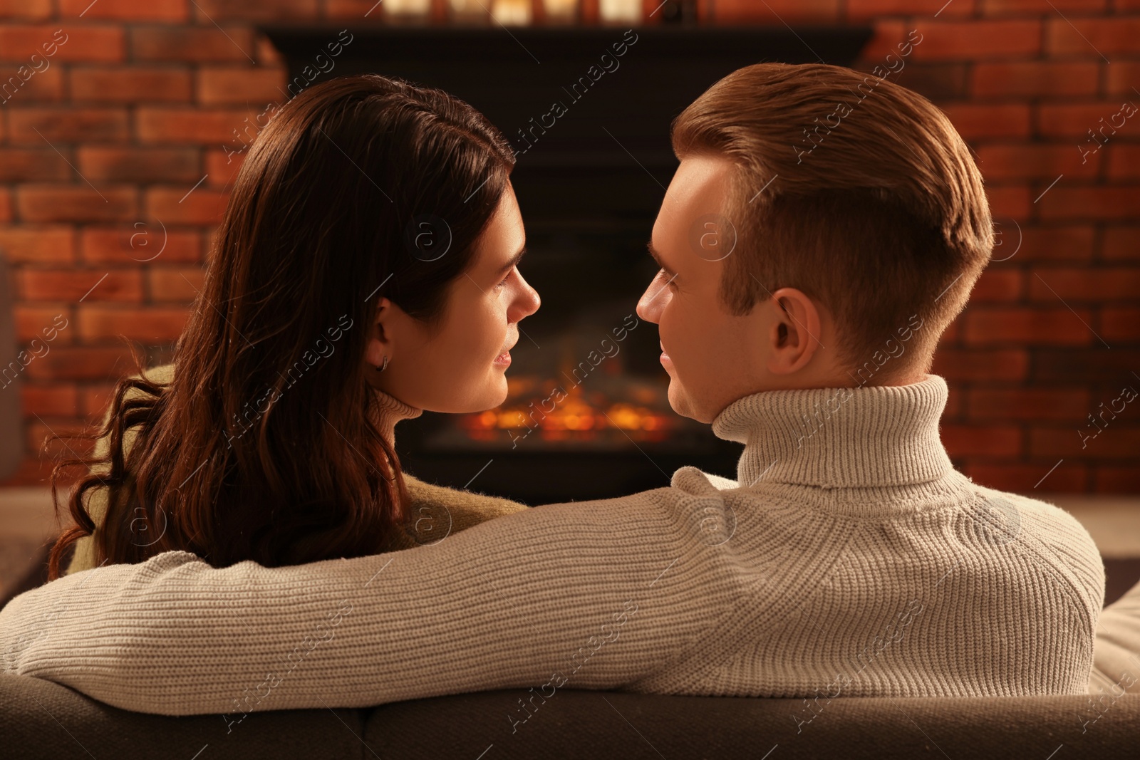 Photo of Lovely couple spending time together near fireplace at home