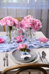 Photo of Stylish table setting with beautiful peonies, napkin and blank card indoors