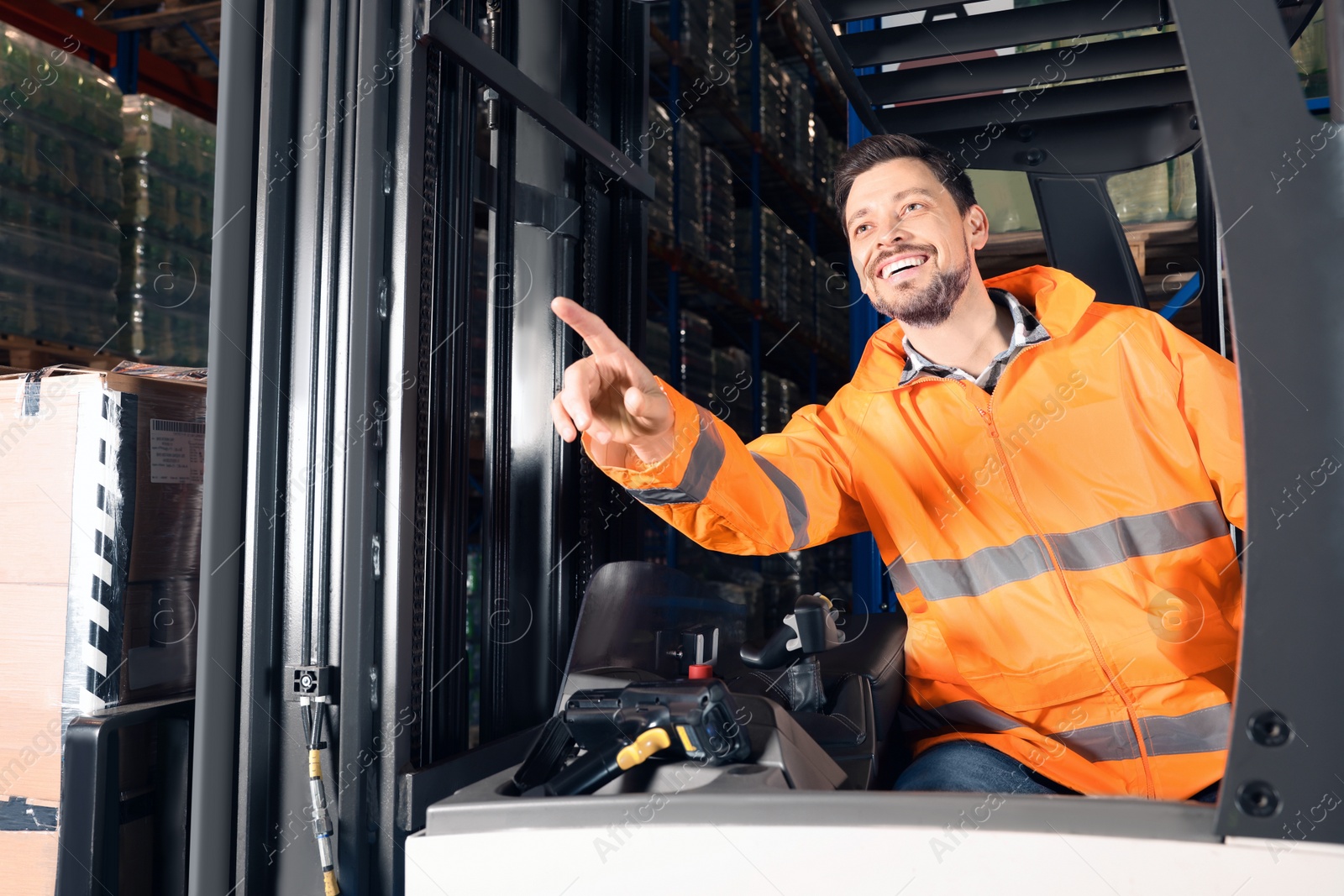 Photo of Happy worker sitting in forklift truck at warehouse