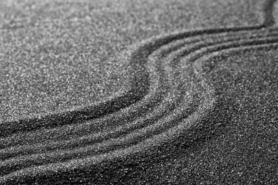Photo of Pattern on decorative black sand, closeup. Zen and harmony