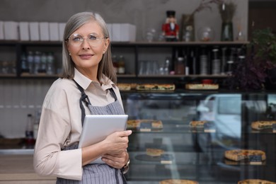 Photo of Business owner with tablet in her cafe, space for text