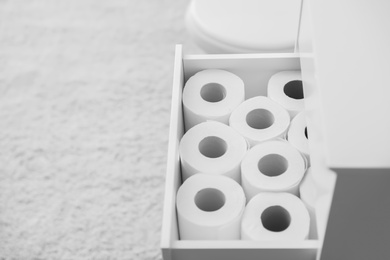 Open cabinet drawer with toilet paper rolls in bathroom. Space for text