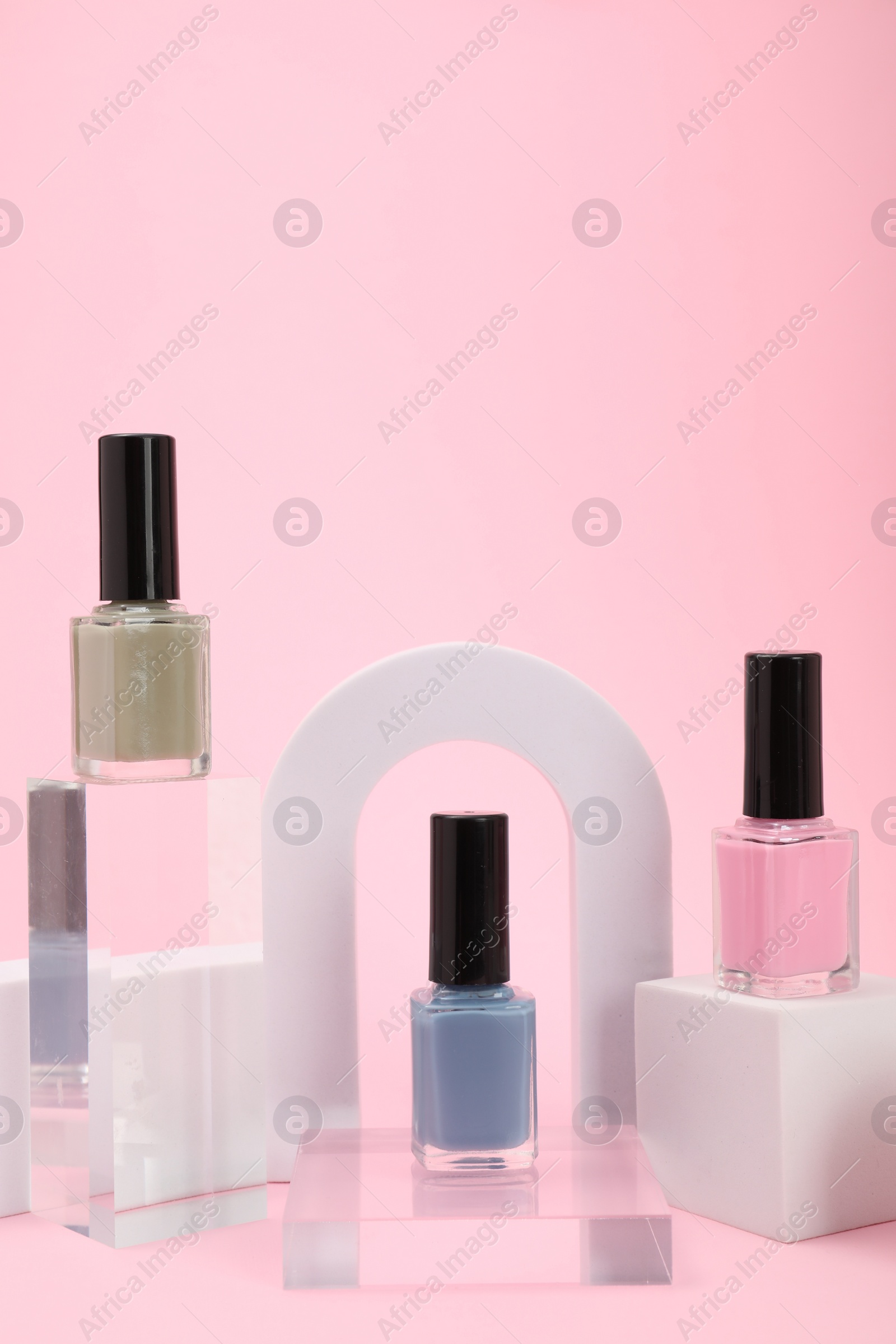 Photo of Stylish presentation of nail polishes on pink background