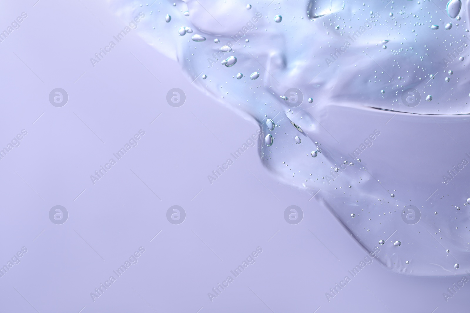 Photo of Transparent cleansing gel on violet background, top view with space for text. Cosmetic product