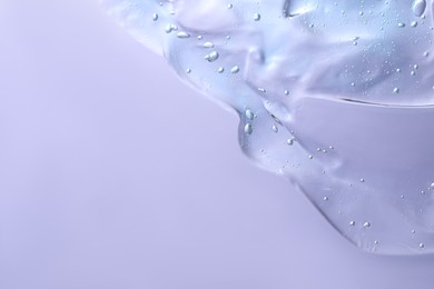 Transparent cleansing gel on violet background, top view with space for text. Cosmetic product