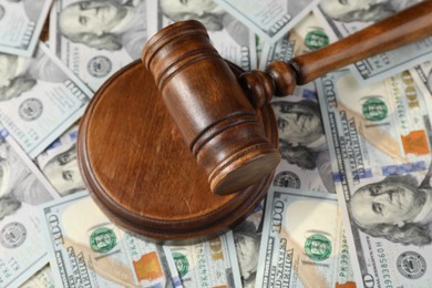 Photo of Wooden judge's gavel on dollar banknotes, closeup